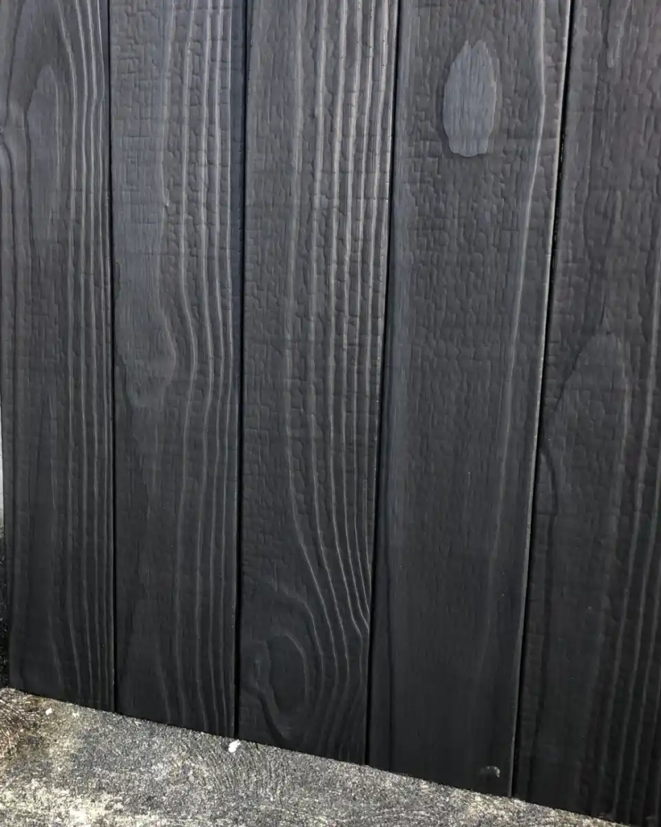 Charred timber fence boards close up UK — carbonised surface texture and grain detail