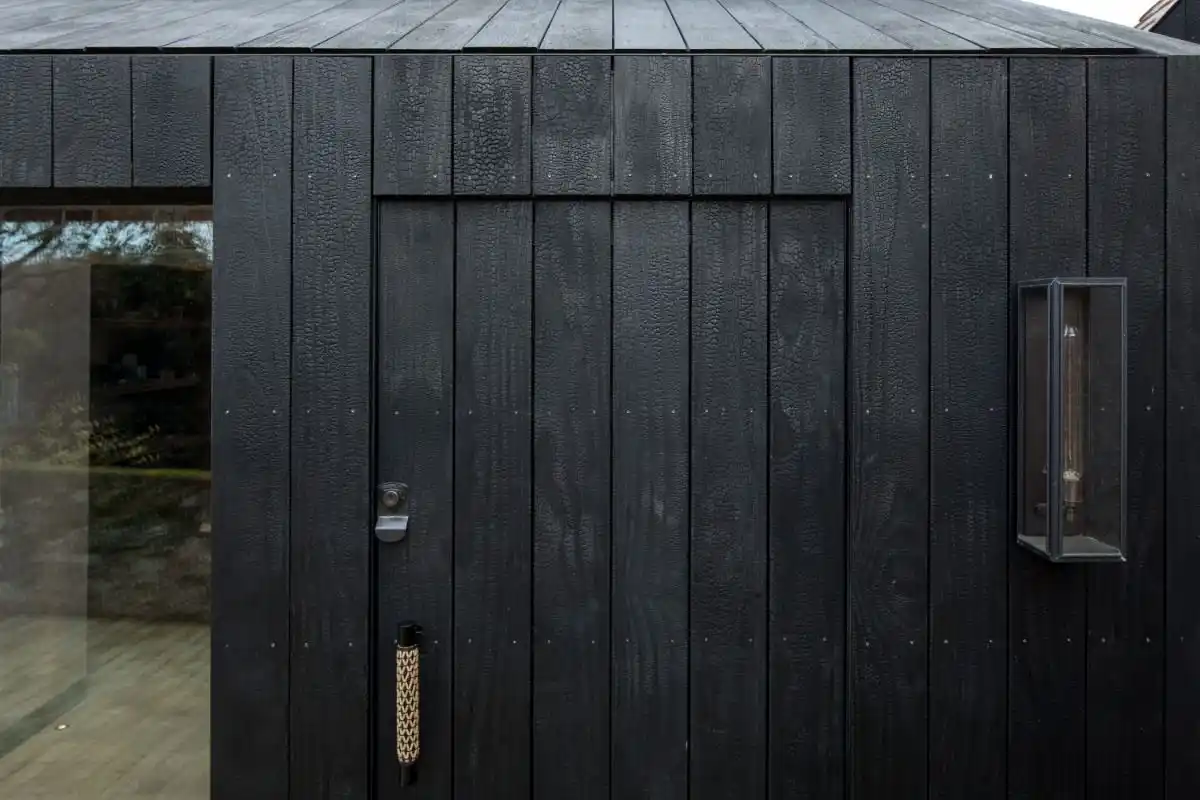 Deep charred timber cladding on UK house exterior — bold black facade with alligator skin texture