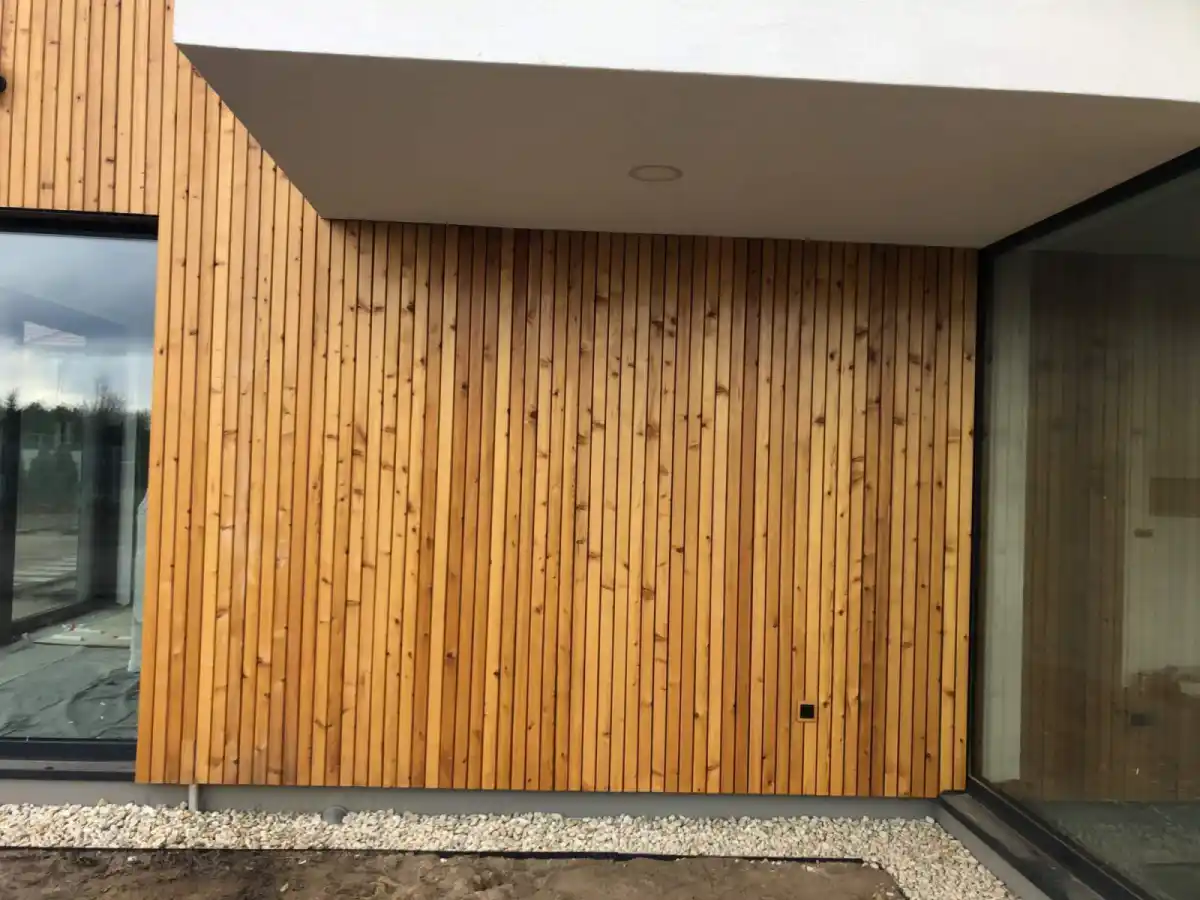 Siberian larch cladding vertical rainscreen on UK residential building — natural golden brown finish